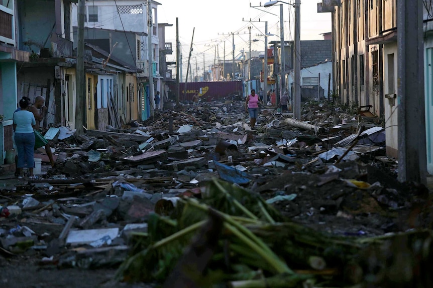 A woman walks along a street covered in debris in Baracoa, Cuba.