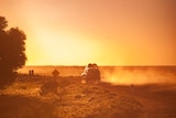 The back of a car on an outback road with the sunset.