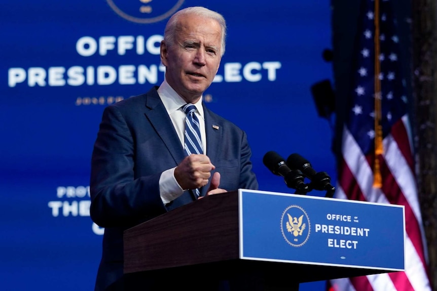 President-elect Joe Biden speaks at a lectern with a blue background behind him