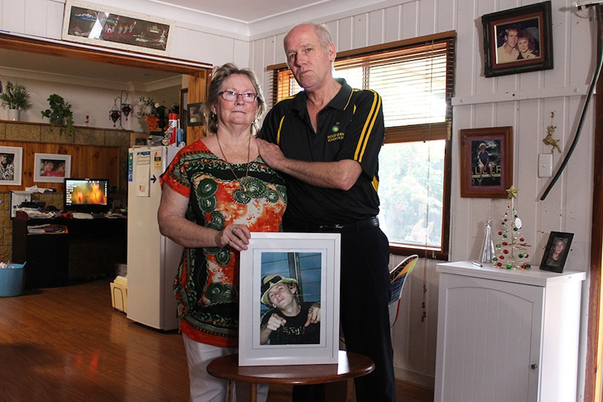 Brett and Bonnie Scovell hug while holding photos of their son Sean, at their home in Biggenden in central Queensland.