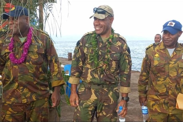 Three military personnel stand next to each other.