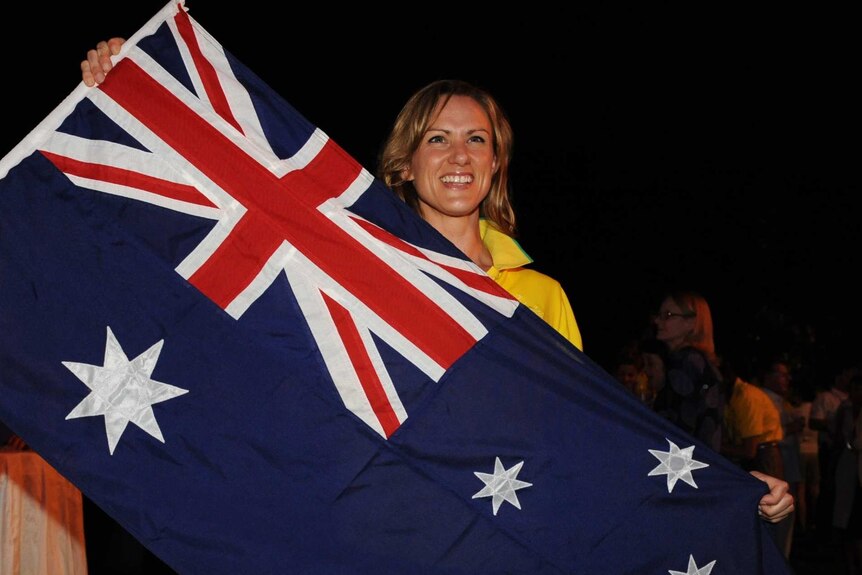 Sharelle McMahon holding the Australian flag and smiling