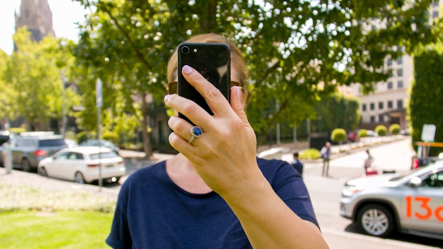 A woman hold a smart phone in front of her face.
