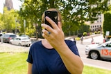 A woman hold a smart phone in front of her face.