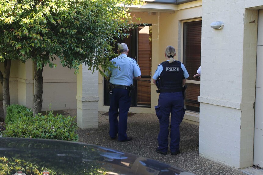 Police from behind at a suburban home