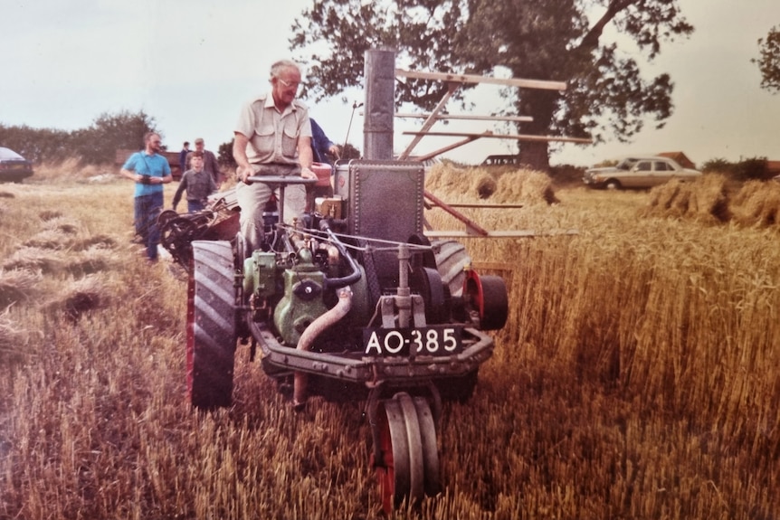 A man driving a green tractor through a wheat field 
