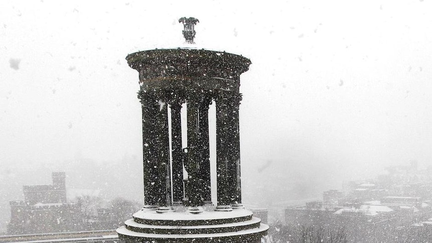 People stand in the snow on Calton Hill in Edinburgh.