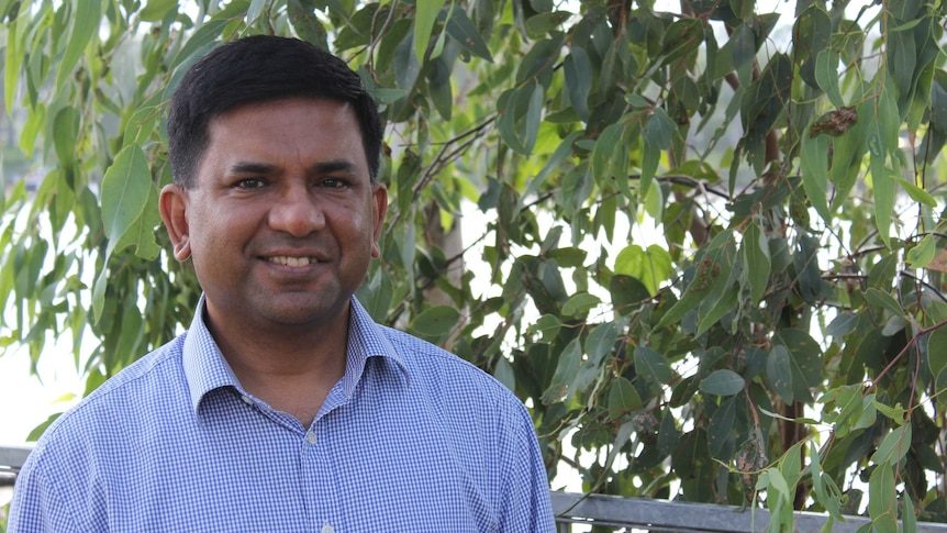 A portrait photo of a man, with gum leaves and a river in the background