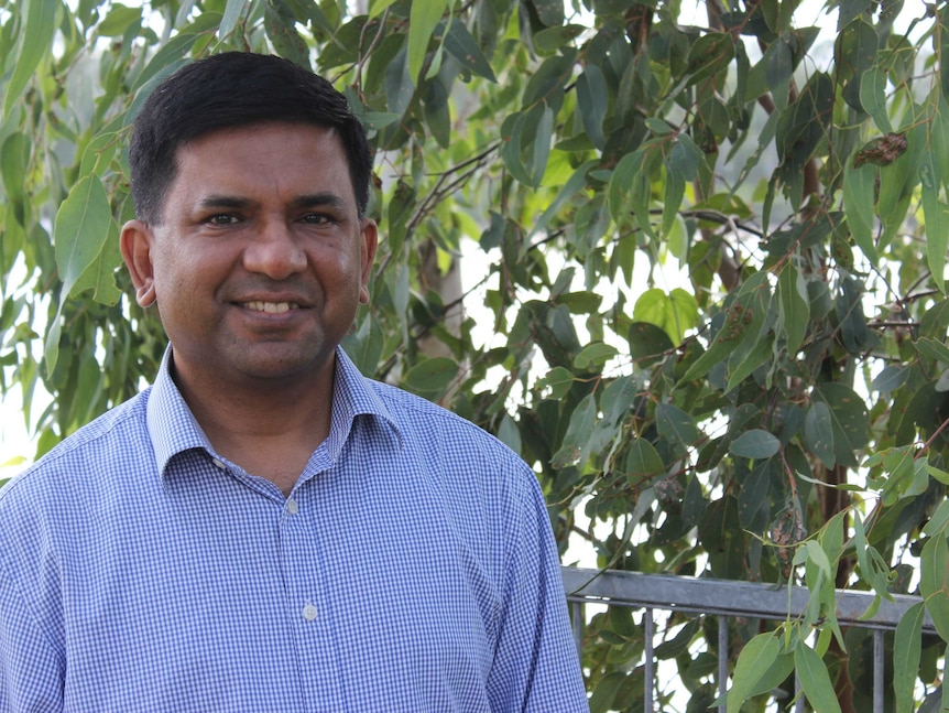 A portrait photo of a man, with gum leaves and a river in the background