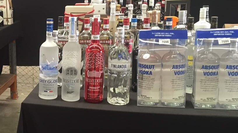 Several rows of spirits sitting on two tables.