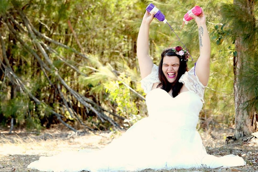 Kira Coleman sits on the ground, pours paint on her wedding dress