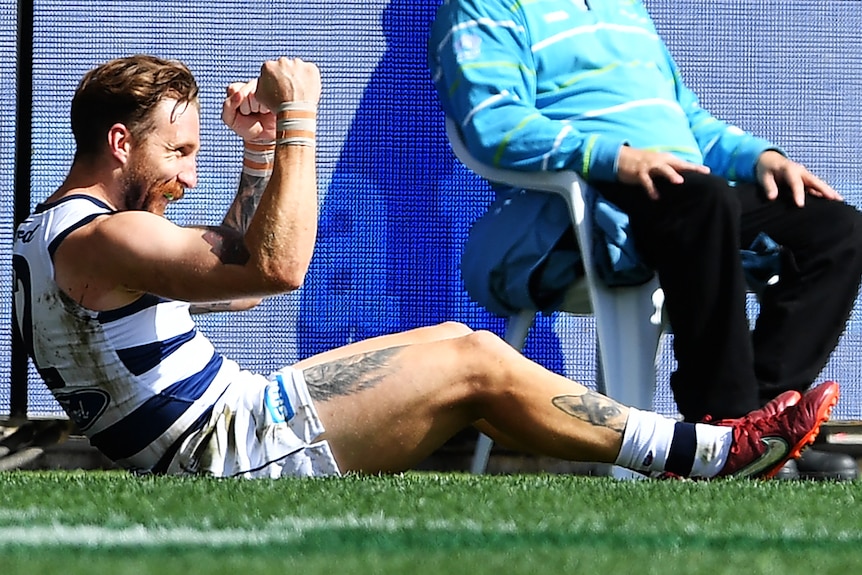 Zach Tuohy sits on the ground outside the boundary line and pumps his fists in celebration