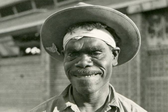 An Aboriginal man in a black and white photo smiling at the camera