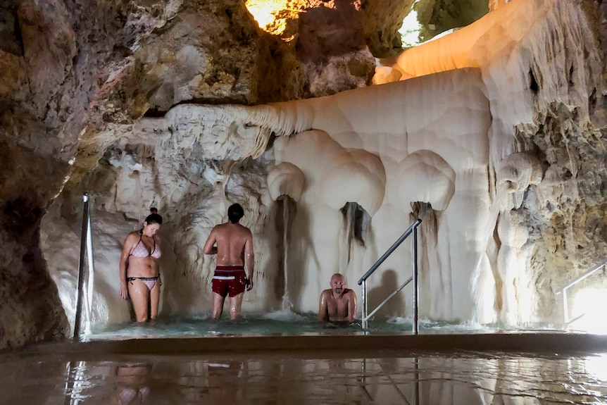 Two people standing inside a spa in front of a cave wall