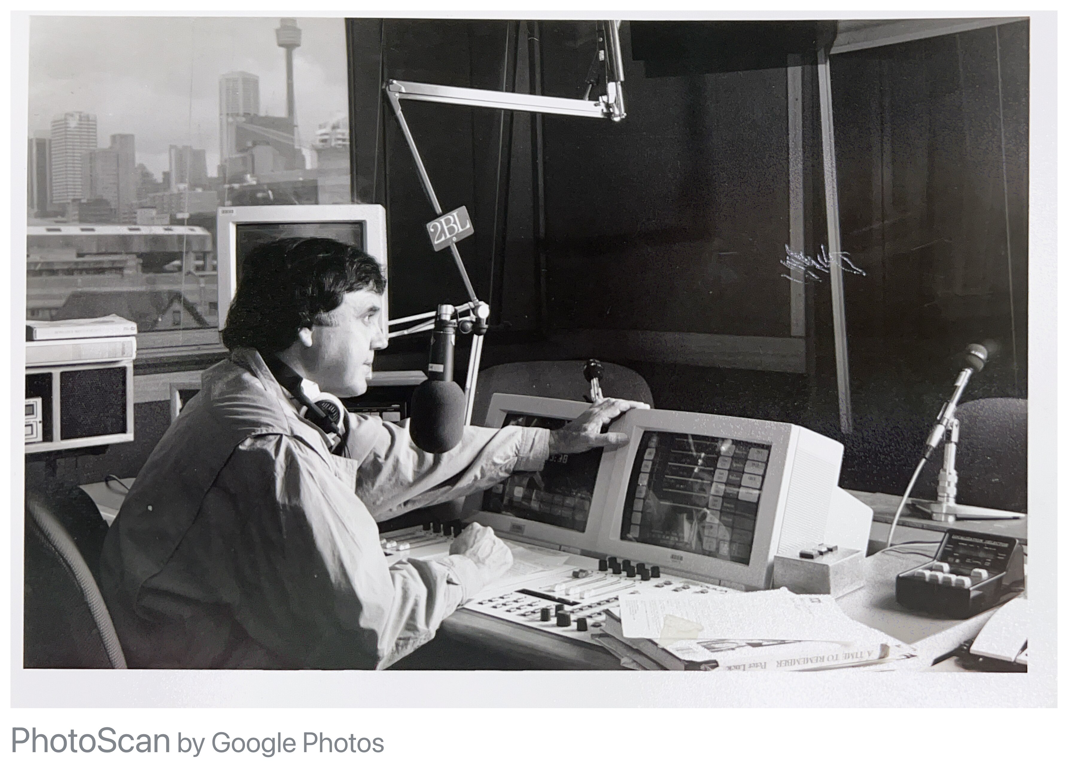 A black and white photos of a man speaking into a microphone in a studio