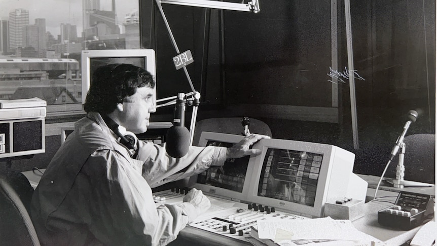 A black and white photos of a man speaking into a microphone in a studio