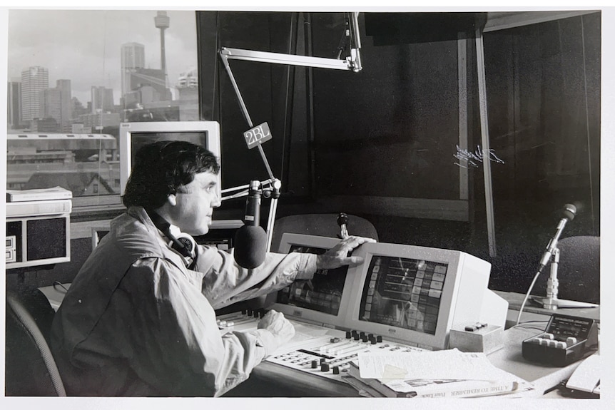 A black and white photos of a man speaking into a microphone in a studio