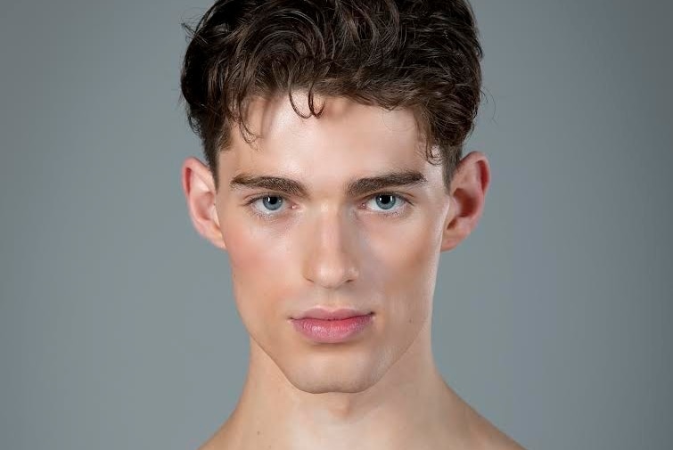 Close up of a chiseled jaw young man wearing stage makeup.