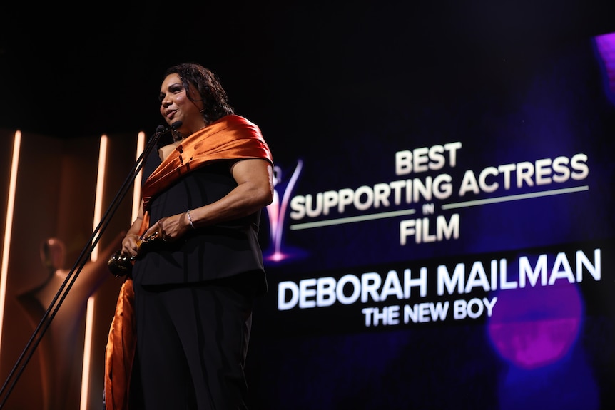 Deborah Mailman in front of a sign which says Best Supporting Actress in Film