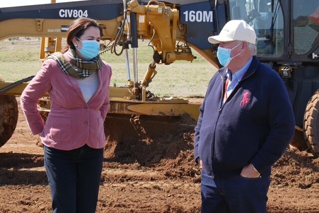 Queensland Premier Annastacia Palaszczuk and businessman John Wagner chat in front of earthmoving equipment.
