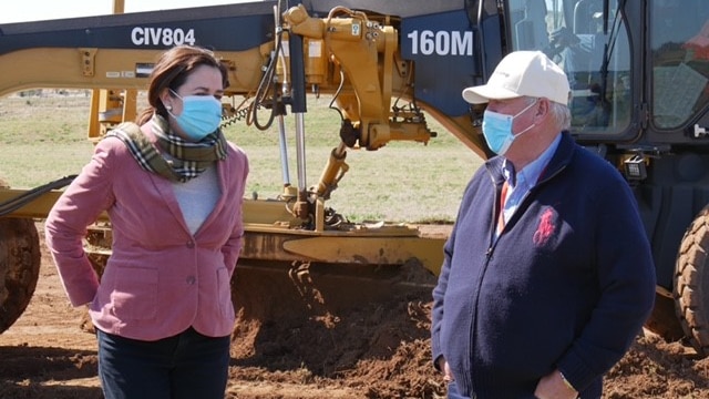 Queensland Premier Annastacia Palaszczuk and businessman John Wagner chat in front of earthmoving equipment.