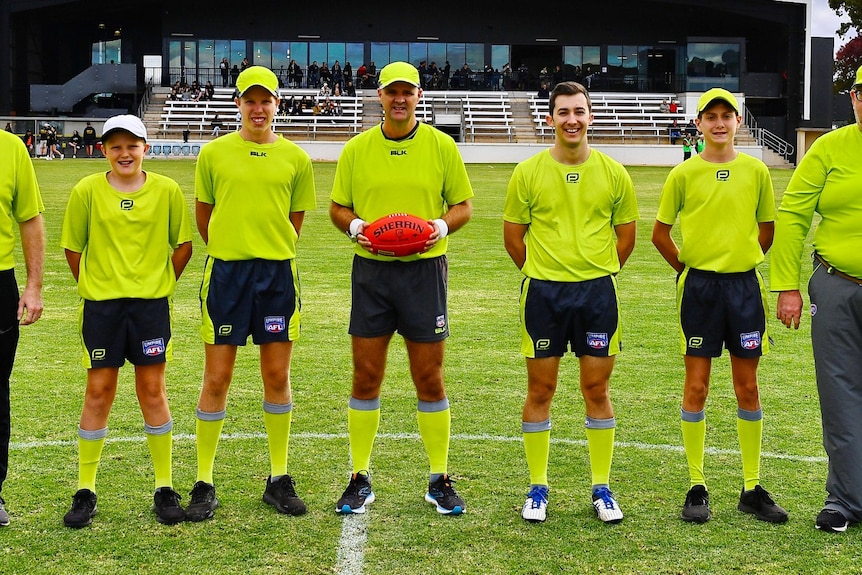 A group of men wearing fluro green shirts standing in a row. 