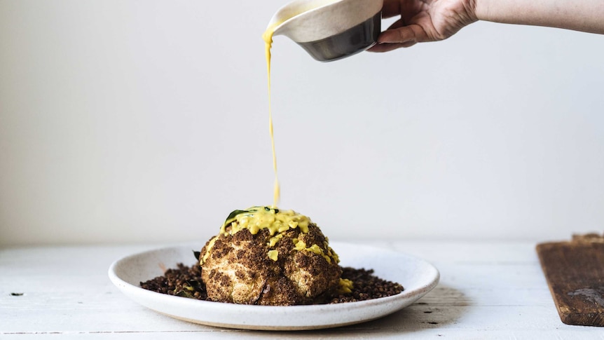 Turmeric coconut sauce is poured over a roasted coconut and fried lentils from a height, a dramatic dish for special occasions.