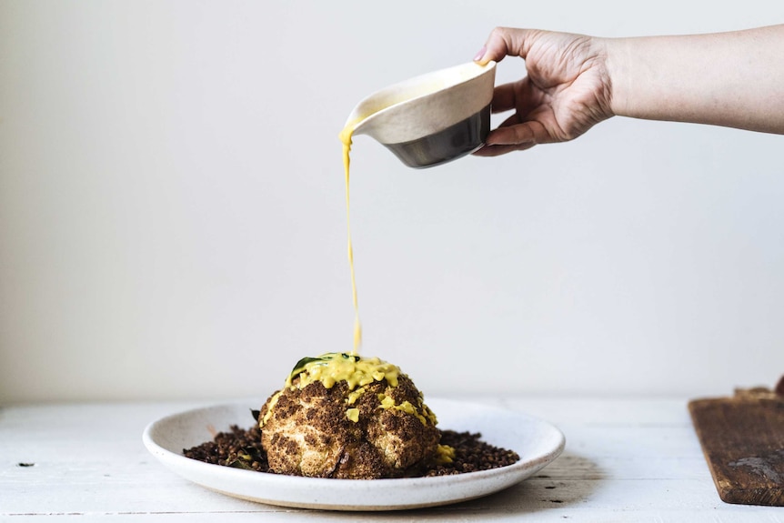 Turmeric coconut sauce is poured over a roasted coconut and fried lentils from a height, a dramatic dish for special occasions.