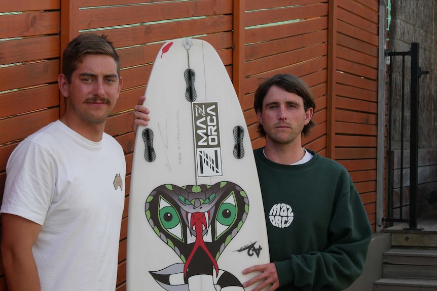 The pair stand by a fence with a board in between them