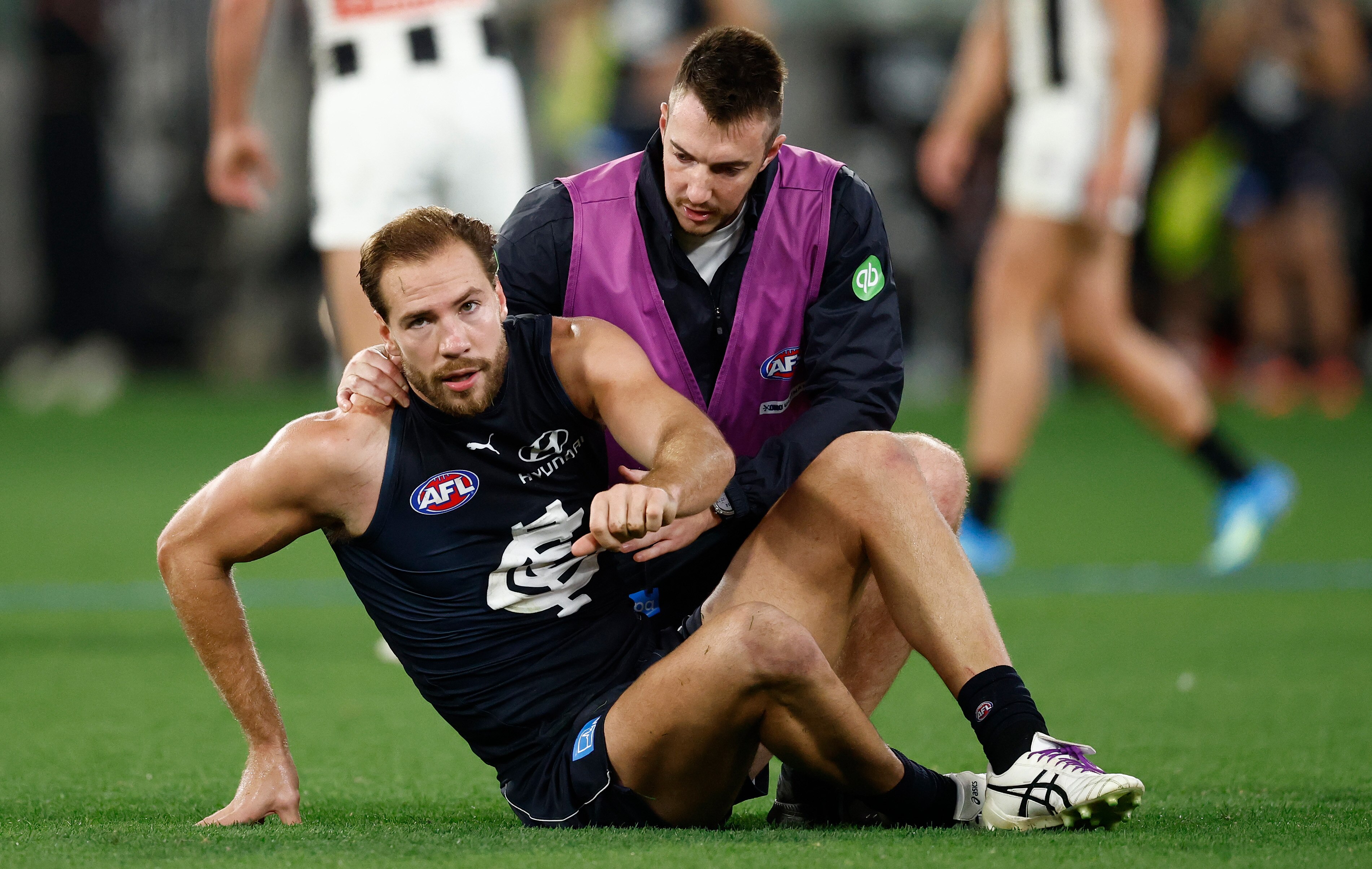 Harry McKay is helped by a trainer after a concussion