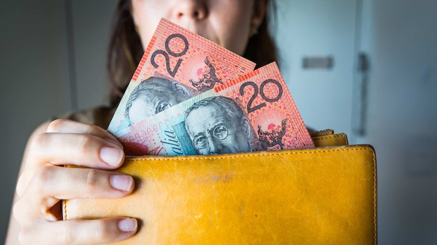 Woman holding a wallet with 20 dollar bills.