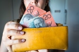 Woman holding a wallet with 20 dollar bills.
