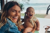 Montana hold her baby daughter blue over a potty in Byron Bay