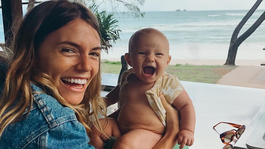 Montana hold her baby daughter blue over a potty in Byron Bay