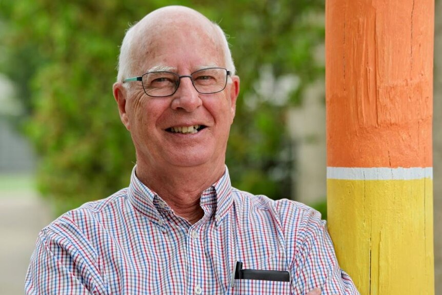Smiling man with glasses leaning against pole