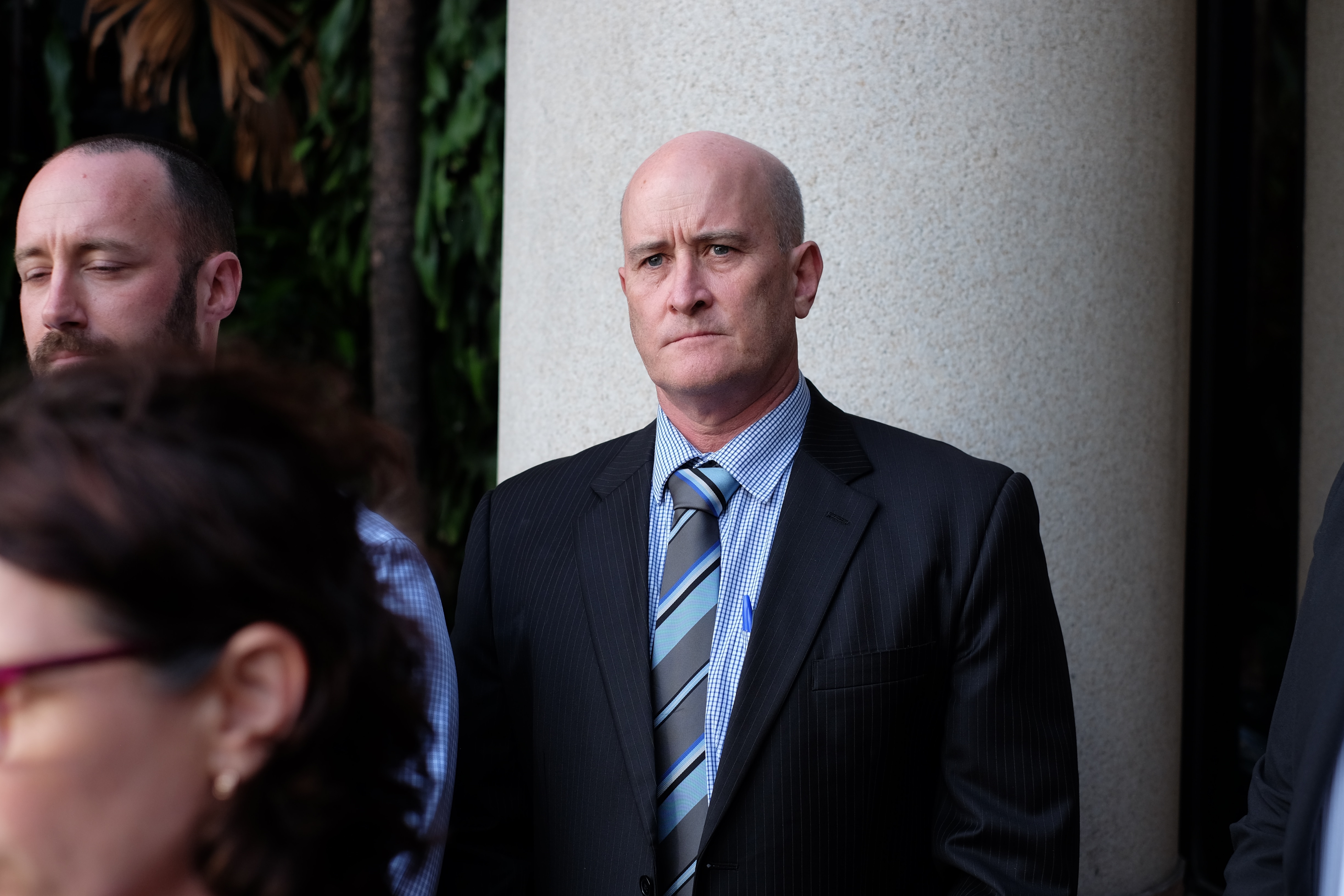 A man in a suit with a bald head looks serious.