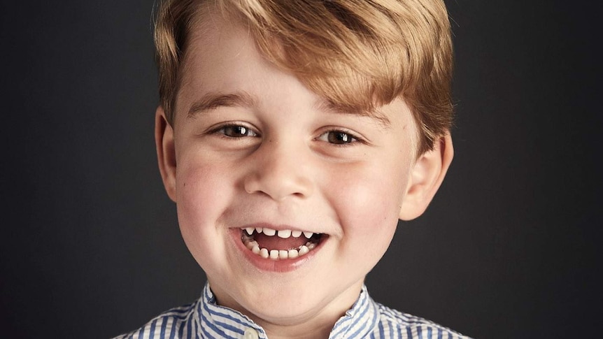 Prince George, wearing a striped shirt with its top button undone, smiles for an official portrait.