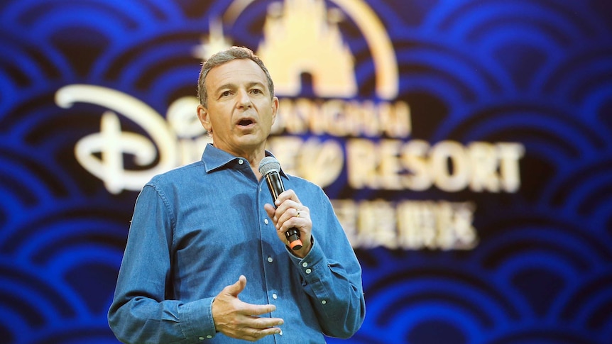 Walt Disney chief executive Bob Iger stands behind a Disney backdrop delivering a speech.