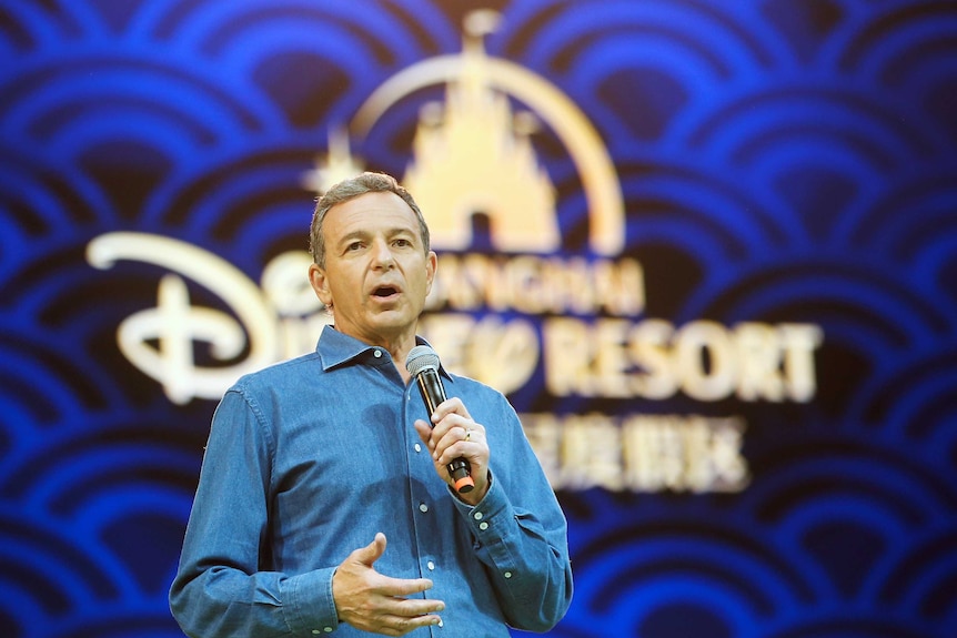 Walt Disney chief executive Bob Iger stands behind a Disney backdrop delivering a speech.