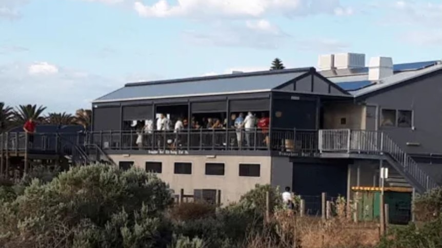 A photo of Semaphore Surf Life Saving Club, from a distance, showing people gathered on the balcony