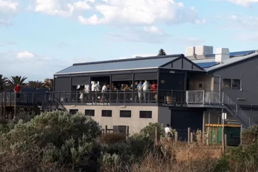 A photo of Semaphore Surf Life Saving Club, from a distance, showing people gathered on the balcony
