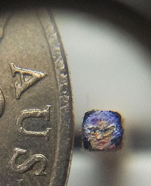 A miniature oill painting of Barry Humphries' character Dame Edna next to a 20 cent piece