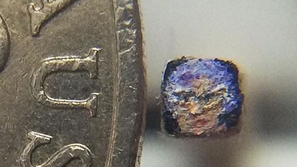 A miniature oill painting of Barry Humphries' character Dame Edna next to a 20 cent piece
