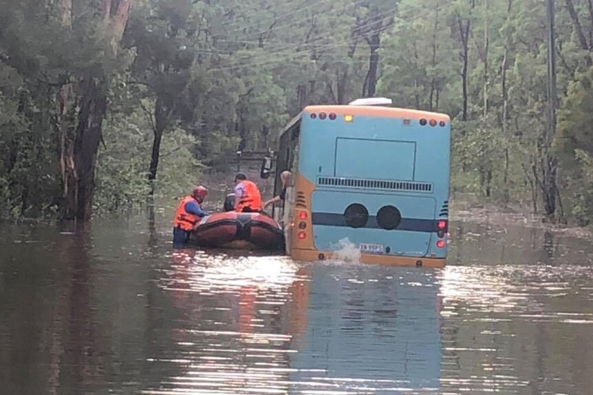 A boat next to a school bus caught in flood water