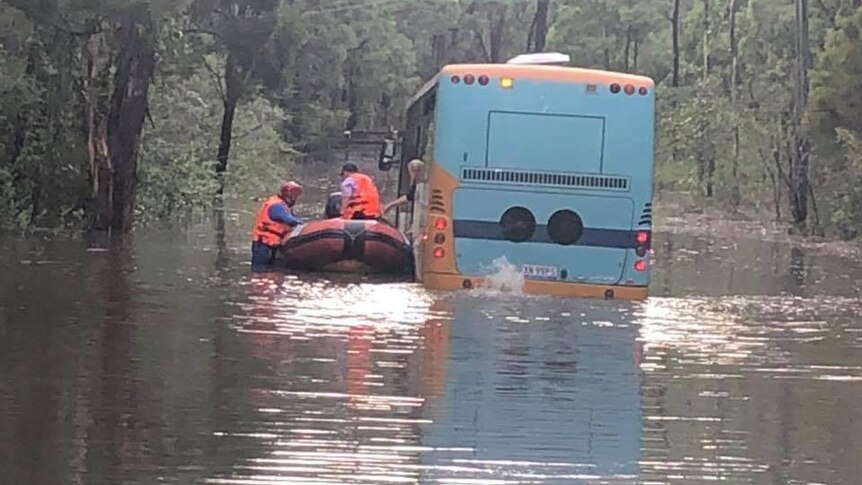 a boat next to a school bus caught in flood water