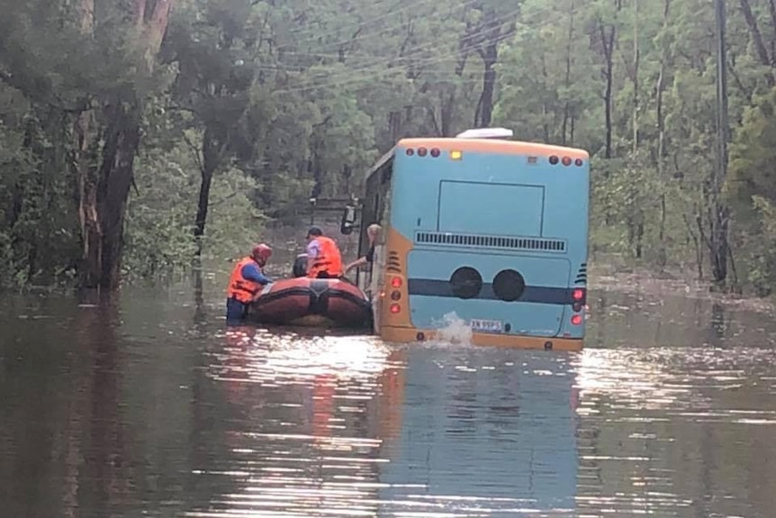 a boat next to a school bus caught in flood water