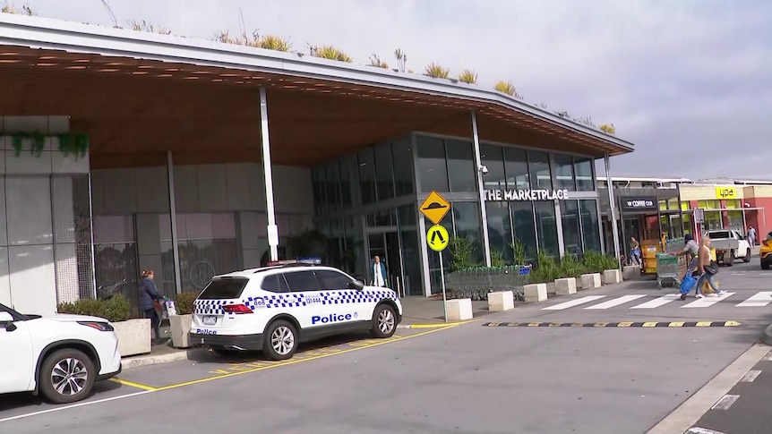 A police car is parked at the front of a shopping centre.