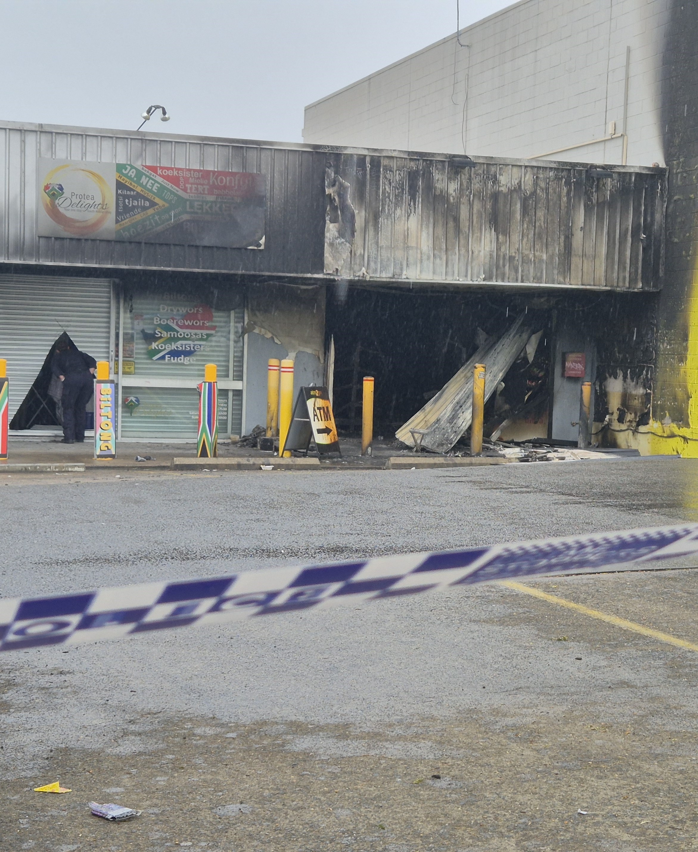 A sign for an ATM outside a shop that has been destroyed by fire.