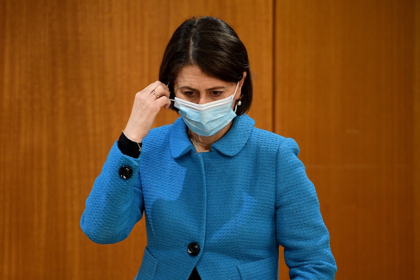 a woman about to remove a face mask 