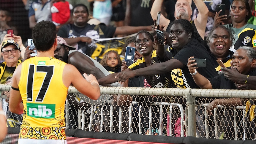 A Richmond AFL player reaches out to Indigenous football fans after a game in Darwin.